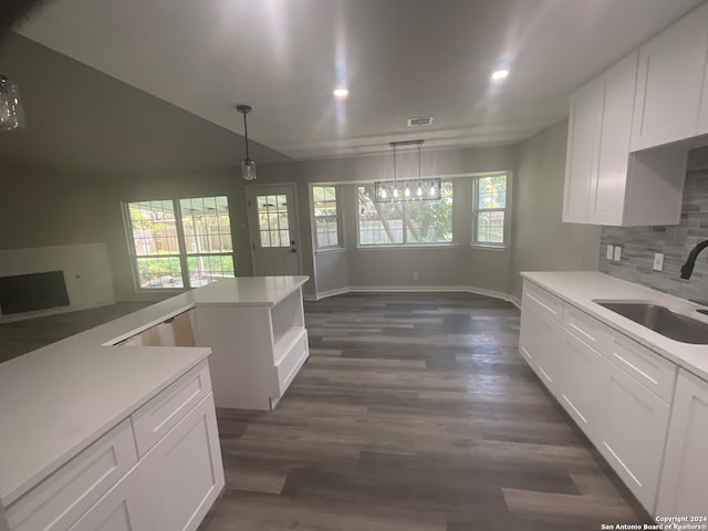 kitchen with white cabinets, decorative backsplash, sink, and hanging light fixtures