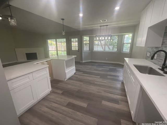 kitchen with pendant lighting, sink, dark hardwood / wood-style floors, a notable chandelier, and white cabinetry