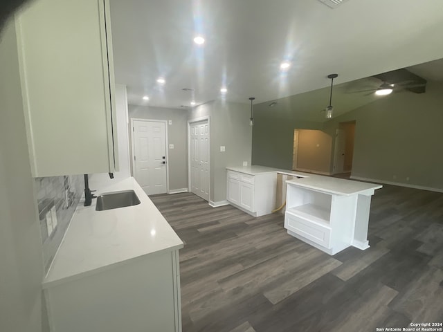 kitchen featuring decorative backsplash, dark wood-type flooring, sink, a center island, and white cabinetry