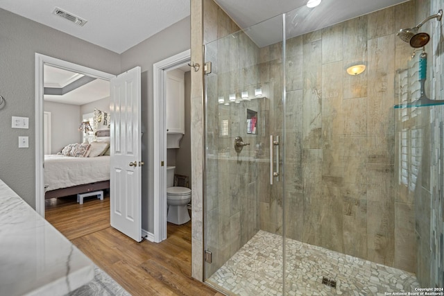 735 Hot Shot Ln, Mcqueeney, TX 78123 - bathroom featuring wood finished floors, ensuite bath, toilet, visible vents, and a stall shower