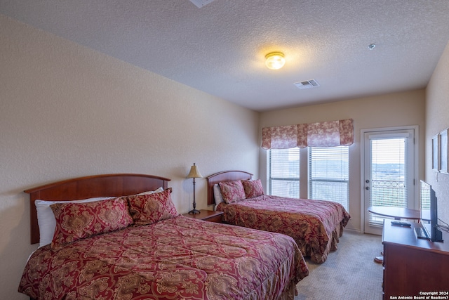 carpeted bedroom with a textured ceiling and access to exterior