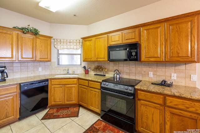 kitchen featuring sink, light tile patterned flooring, black appliances, and backsplash