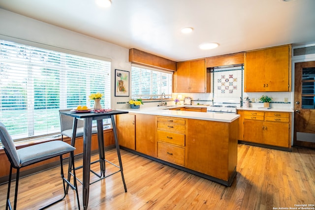 kitchen featuring light hardwood / wood-style floors, kitchen peninsula, backsplash, and a wealth of natural light