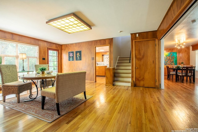 dining area with stairs, an inviting chandelier, light wood-style floors, and wood walls