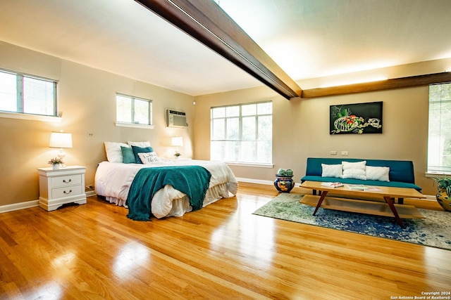 bedroom featuring multiple windows, an AC wall unit, baseboards, and wood finished floors