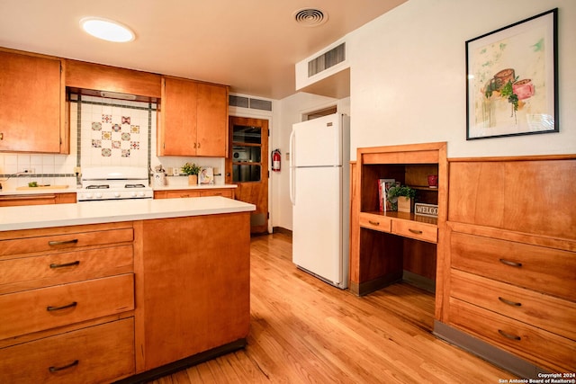 kitchen featuring decorative backsplash, light hardwood / wood-style floors, and white appliances