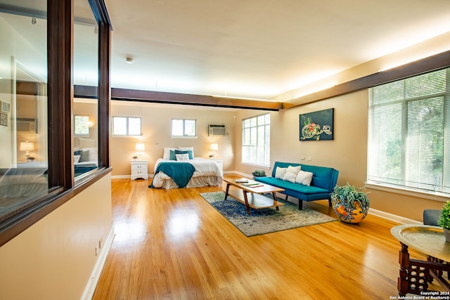 bedroom with multiple windows, wood-type flooring, and a wall mounted air conditioner