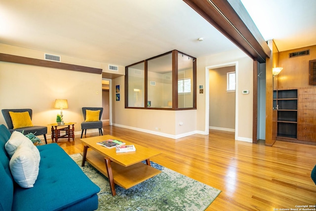 living area featuring visible vents, light wood-style flooring, and baseboards