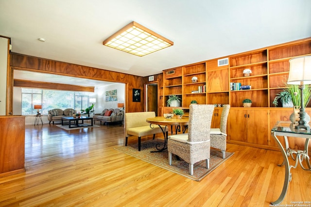 sitting room with light wood-type flooring, visible vents, and wood walls