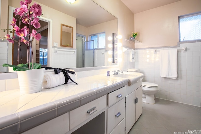 bathroom with a wealth of natural light, vanity, tile patterned floors, and tile walls