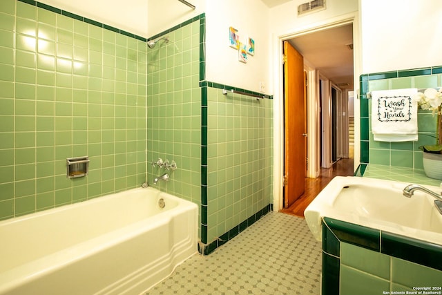 full bathroom featuring visible vents, shower / tub combination, tile walls, wainscoting, and vanity