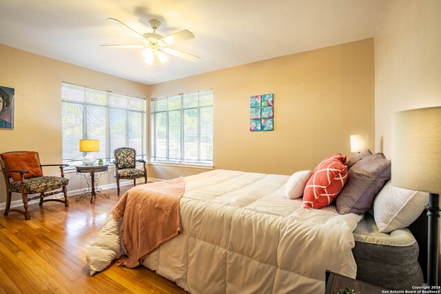 bedroom with multiple windows, ceiling fan, and wood-type flooring