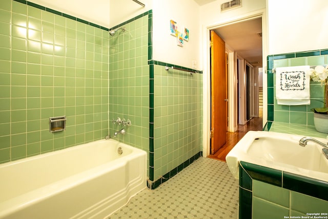 bathroom with vanity, tile walls, and tiled shower / bath