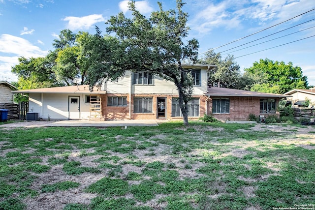 view of front facade with brick siding, cooling unit, a patio, and a front lawn