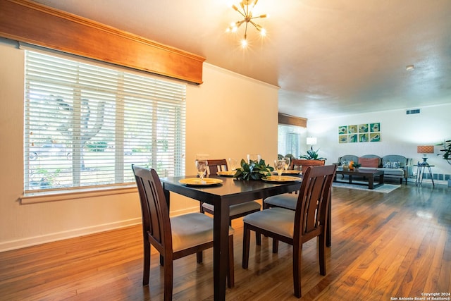 dining area featuring wood finished floors, visible vents, baseboards, crown molding, and a chandelier