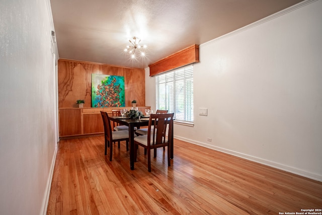 dining space with crown molding, light hardwood / wood-style floors, and a notable chandelier