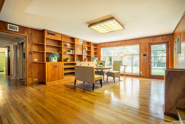 home office with light hardwood / wood-style flooring and wooden walls