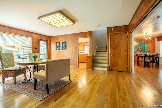 dining room featuring a chandelier, wood walls, and light hardwood / wood-style flooring