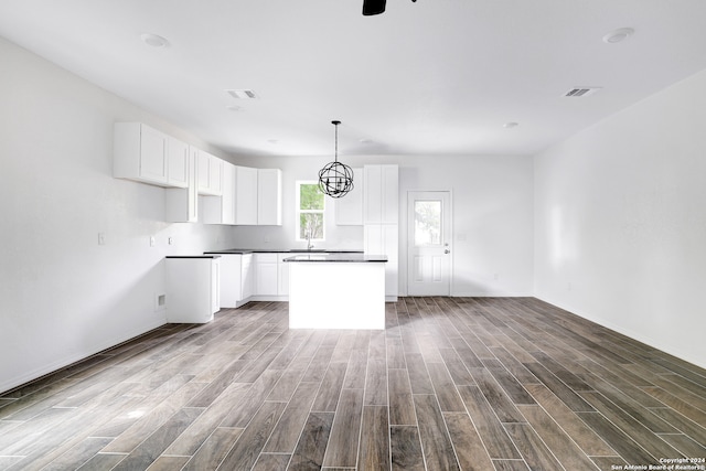 kitchen with white cabinetry, hardwood / wood-style flooring, sink, and a center island