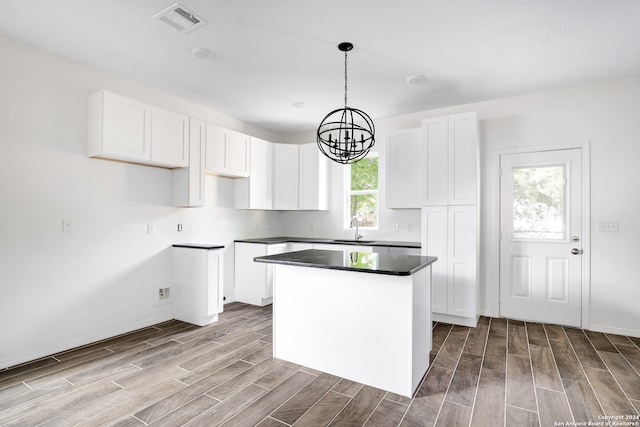 kitchen with light wood-type flooring, a chandelier, hanging light fixtures, white cabinetry, and a center island