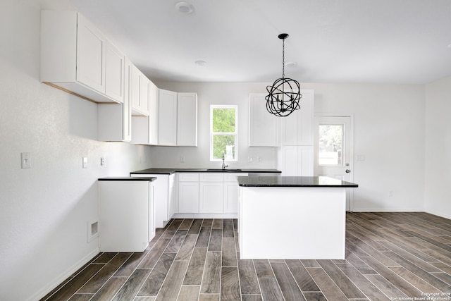 kitchen with white cabinets, decorative light fixtures, a center island, and dark hardwood / wood-style floors