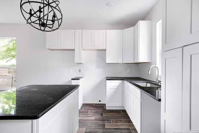 kitchen featuring sink, an inviting chandelier, dark hardwood / wood-style floors, white cabinetry, and pendant lighting