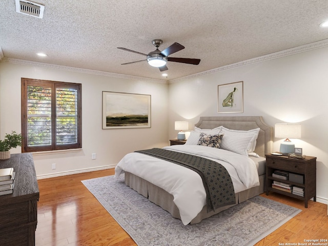 bedroom featuring wood-type flooring, a textured ceiling, ceiling fan, and crown molding