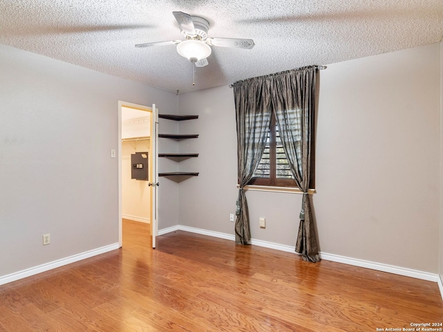 unfurnished room featuring ceiling fan, light wood-type flooring, and a textured ceiling