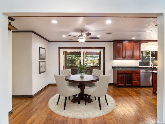 dining area featuring ceiling fan, dark hardwood / wood-style flooring, ornamental molding, and a textured ceiling