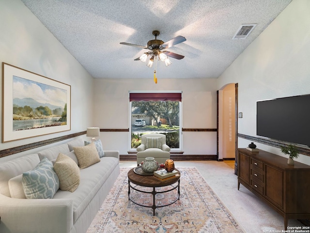 carpeted living room featuring ceiling fan and a textured ceiling