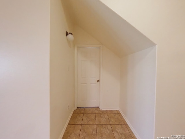 additional living space featuring light tile patterned flooring and lofted ceiling