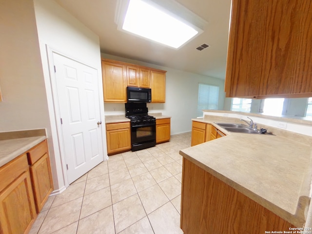 kitchen with light tile patterned flooring, sink, kitchen peninsula, and black appliances