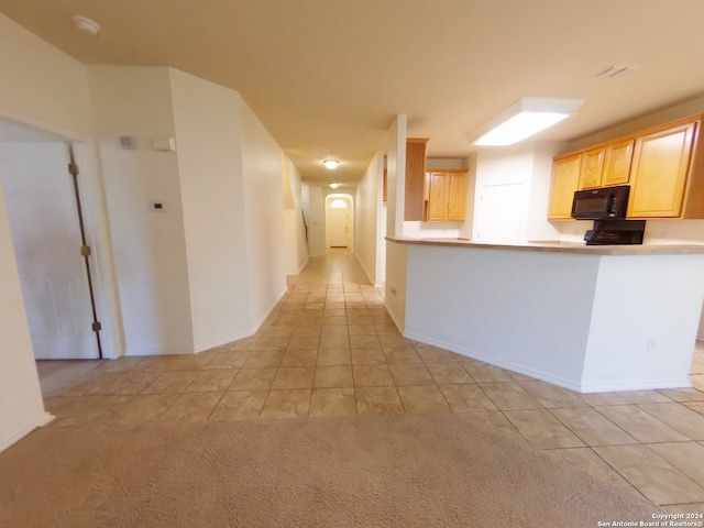 kitchen with light colored carpet, kitchen peninsula, and light brown cabinetry