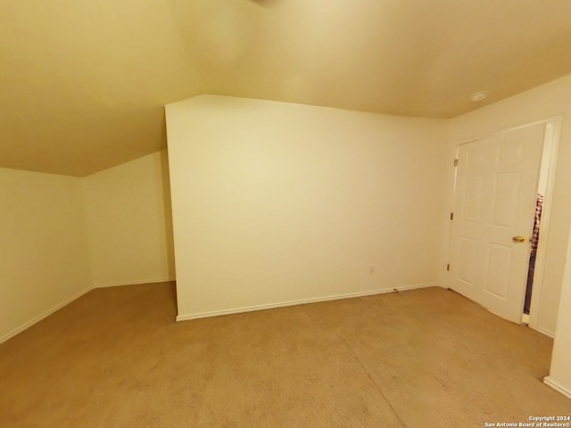 bonus room with vaulted ceiling and light colored carpet