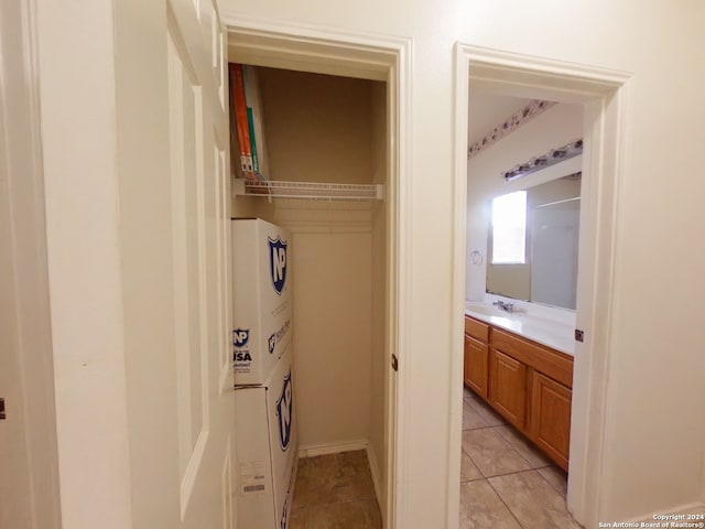 laundry room featuring stacked washer and dryer, sink, and light tile patterned floors