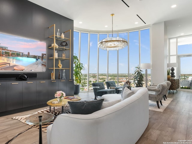 living room featuring a notable chandelier, plenty of natural light, a wall of windows, and hardwood / wood-style floors