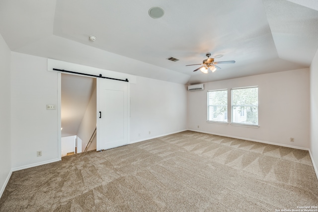 unfurnished bedroom featuring a wall mounted AC, vaulted ceiling, light colored carpet, and a barn door