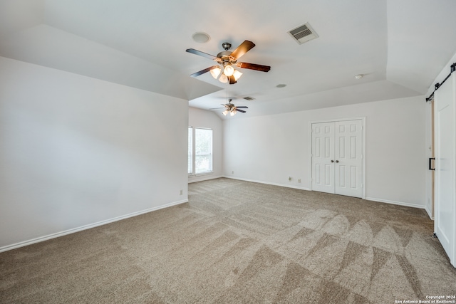 unfurnished room with vaulted ceiling, light colored carpet, ceiling fan, and a barn door