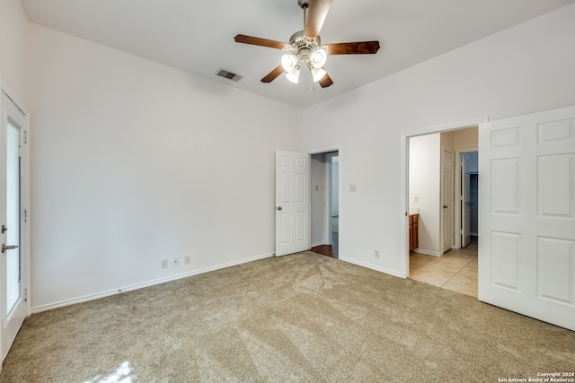 unfurnished bedroom featuring light colored carpet, ceiling fan, and ensuite bath