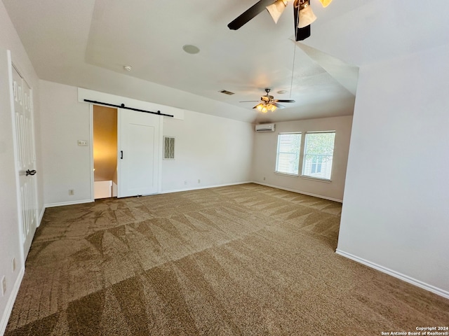 unfurnished bedroom featuring a barn door, ceiling fan, an AC wall unit, and carpet floors