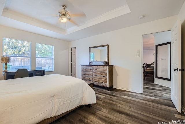 bedroom with ceiling fan, a tray ceiling, and dark hardwood / wood-style floors