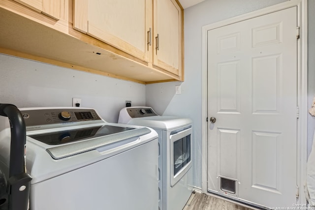 washroom featuring light wood-type flooring, washer and dryer, and cabinets