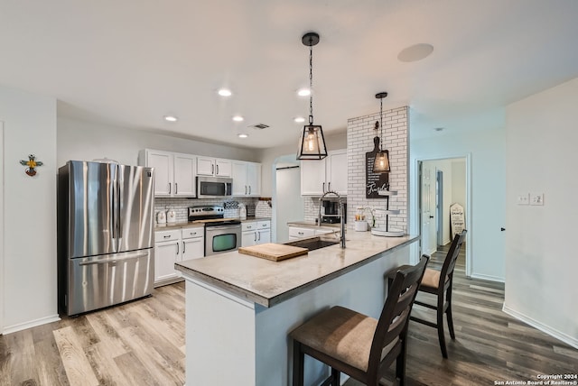 kitchen featuring light wood-type flooring, decorative backsplash, stainless steel appliances, kitchen peninsula, and white cabinets