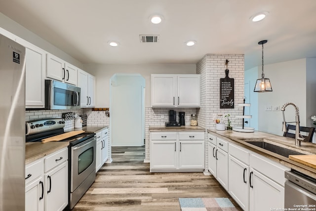 kitchen featuring light hardwood / wood-style flooring, backsplash, pendant lighting, sink, and stainless steel appliances