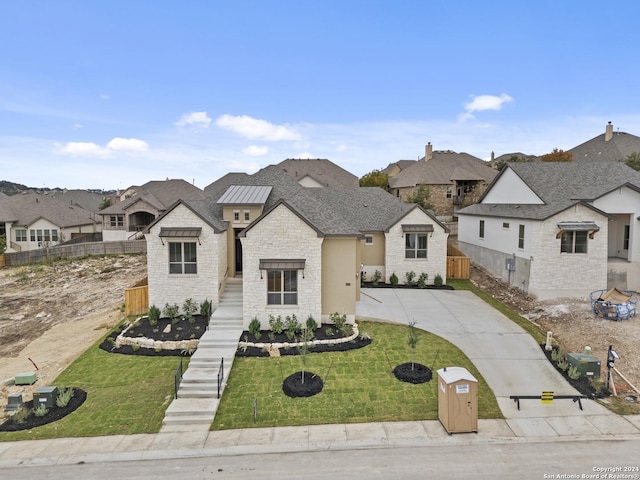 french country inspired facade with a residential view, stone siding, fence, and a front lawn