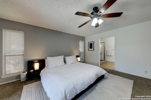 bedroom with light colored carpet, a textured ceiling, ensuite bath, and ceiling fan