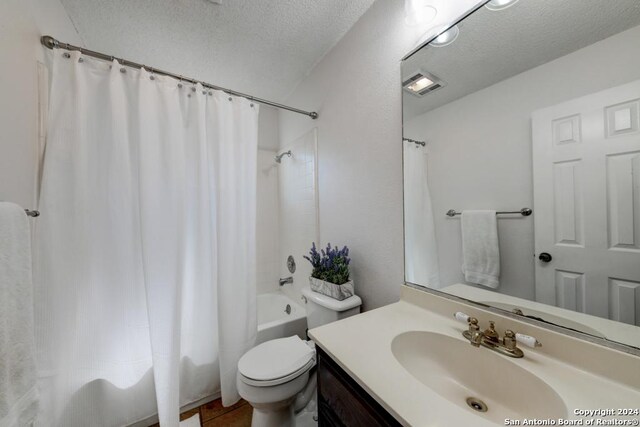 full bathroom featuring shower / bath combo with shower curtain, a textured ceiling, tile patterned flooring, vanity, and toilet