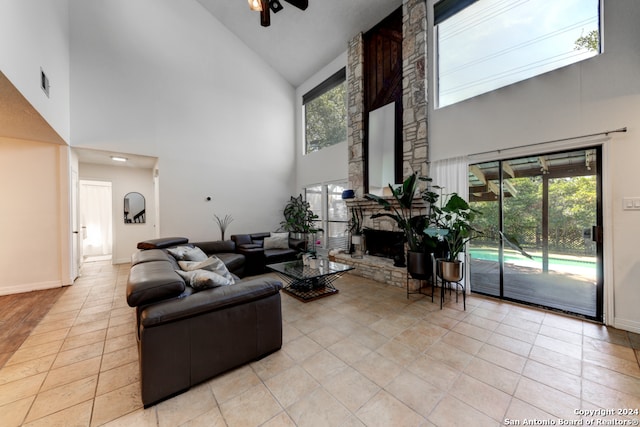 tiled living room featuring ceiling fan, high vaulted ceiling, a healthy amount of sunlight, and a fireplace