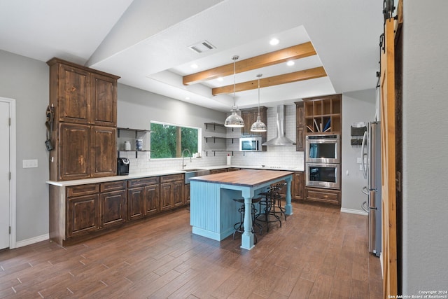 kitchen with a raised ceiling, wall chimney exhaust hood, wood counters, a center island, and open shelves