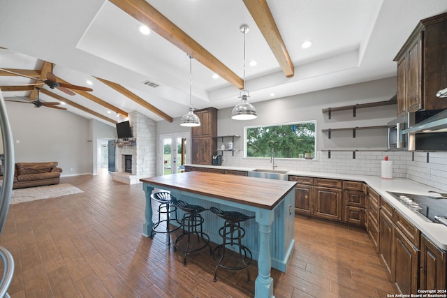 kitchen featuring a center island, black stovetop, dark wood finished floors, wooden counters, and a sink